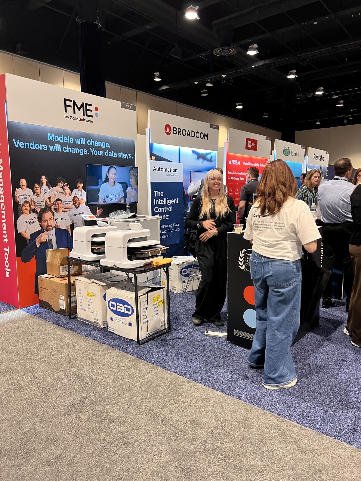 Attendees interacting with product displays at an event booth featuring printed materials and apparel samples
